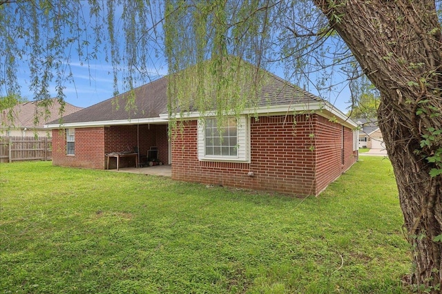 rear view of house with a yard, a shingled roof, fence, and a patio