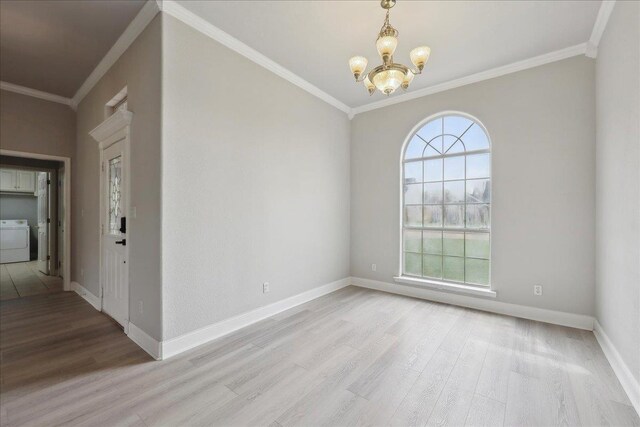 unfurnished room featuring crown molding, baseboards, a notable chandelier, light wood-type flooring, and washer / dryer