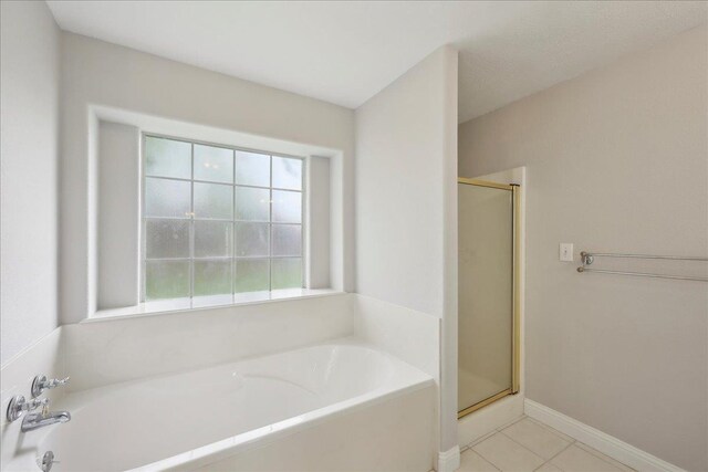 full bath with a stall shower, baseboards, tile patterned flooring, and a bath