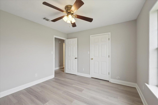 unfurnished bedroom with baseboards, visible vents, a ceiling fan, and light wood finished floors