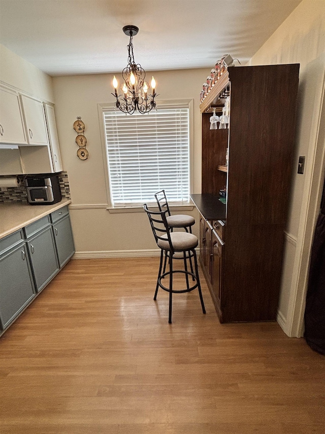 kitchen featuring light wood-style flooring, pendant lighting, baseboards, and a chandelier