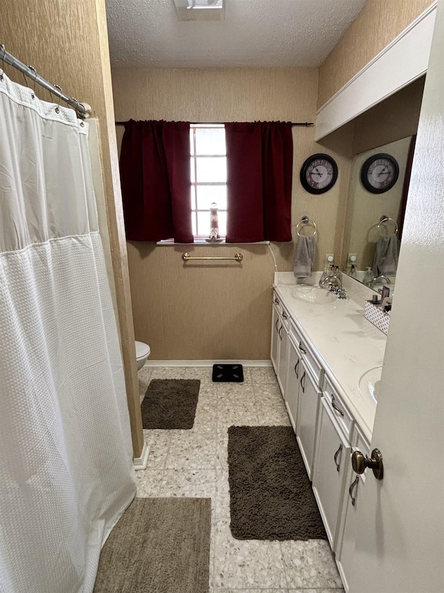 bathroom with toilet, double vanity, tile patterned floors, a textured ceiling, and a sink