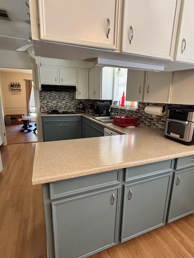 kitchen with visible vents, light wood finished floors, gray cabinets, a sink, and tasteful backsplash