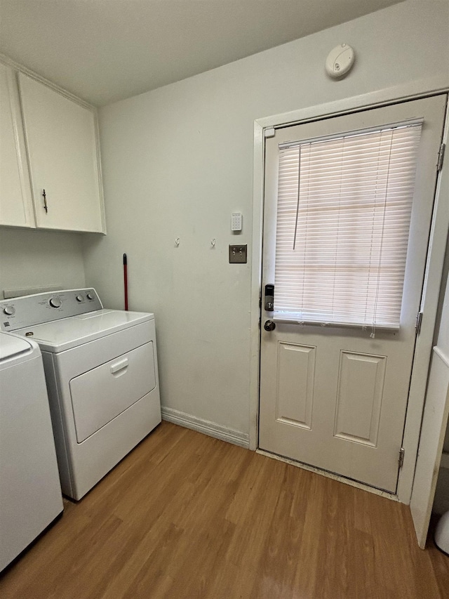 washroom featuring cabinet space, washer and dryer, light wood-style flooring, and baseboards