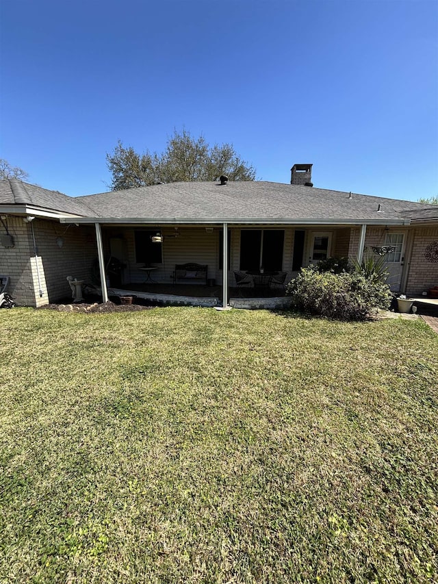 back of house with a lawn, brick siding, and a patio area