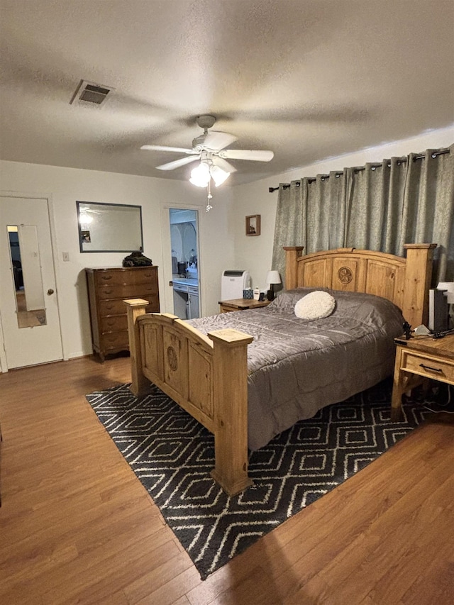 bedroom with visible vents, a textured ceiling, a ceiling fan, and wood finished floors