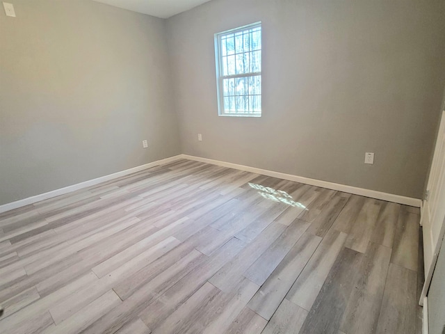 spare room featuring light wood finished floors and baseboards