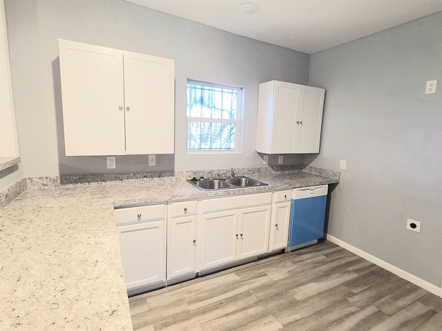 kitchen featuring baseboards, dishwashing machine, a sink, and white cabinets