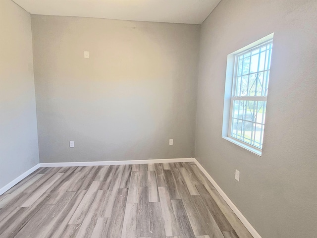 spare room featuring baseboards and wood finished floors