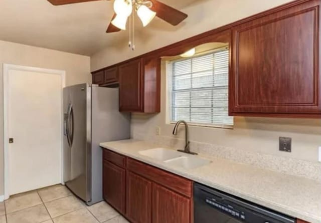 kitchen with light countertops, light tile patterned floors, a sink, freestanding refrigerator, and black dishwasher
