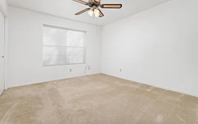 carpeted empty room with a ceiling fan