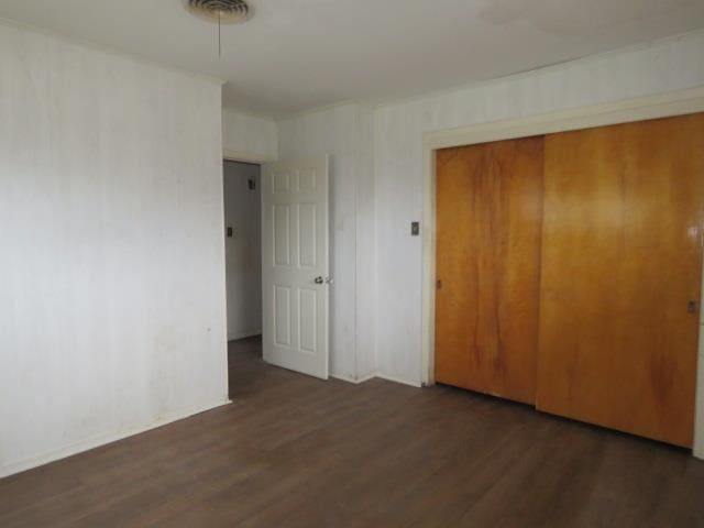 unfurnished bedroom with dark hardwood / wood-style flooring and a closet