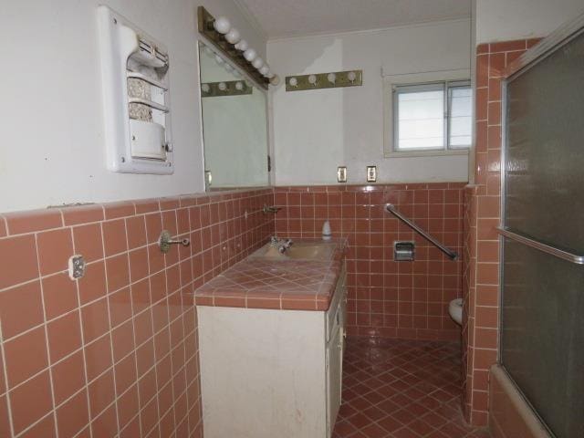 full bathroom with tile patterned floors, vanity, shower / bath combination with glass door, tile walls, and toilet