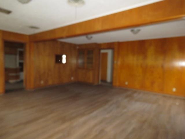 unfurnished living room with hardwood / wood-style floors and wooden walls