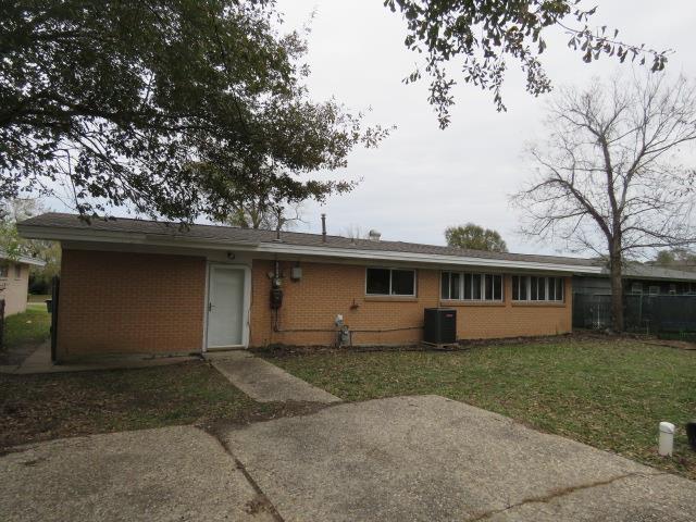 rear view of house featuring cooling unit and a yard