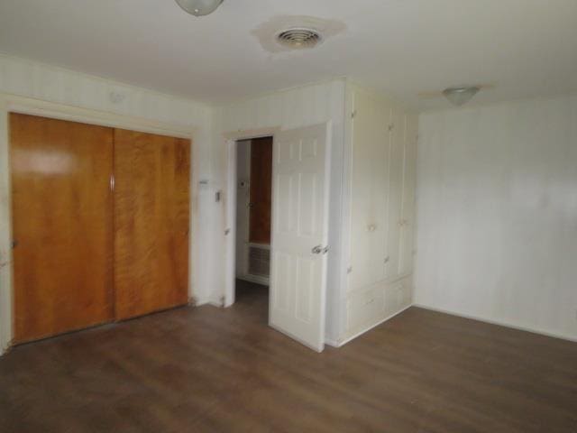 unfurnished bedroom featuring dark hardwood / wood-style flooring and a closet