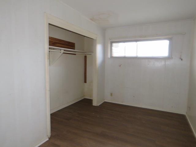 unfurnished bedroom featuring dark hardwood / wood-style floors and a closet