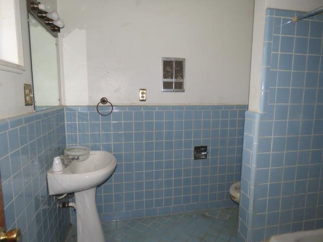 bathroom with walk in shower and tile walls