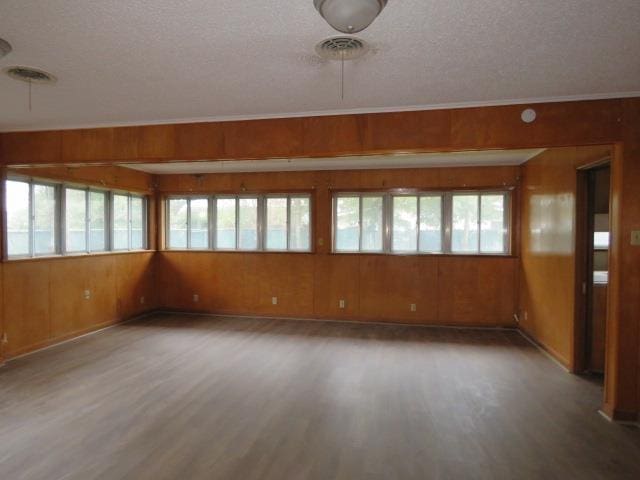 spare room with hardwood / wood-style floors, a textured ceiling, and wooden walls