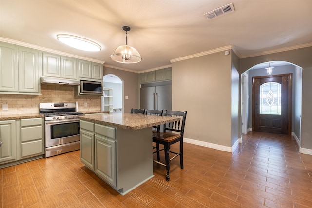 5269 Fairview Dr, Orange, TX 77630 - kitchen with stainless steel appliances, arched walkways, a kitchen breakfast bar, baseboards, and tasteful backsplash
