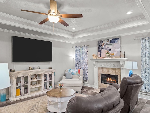 living area featuring ornamental molding, ceiling fan, wood finished floors, and a tray ceiling