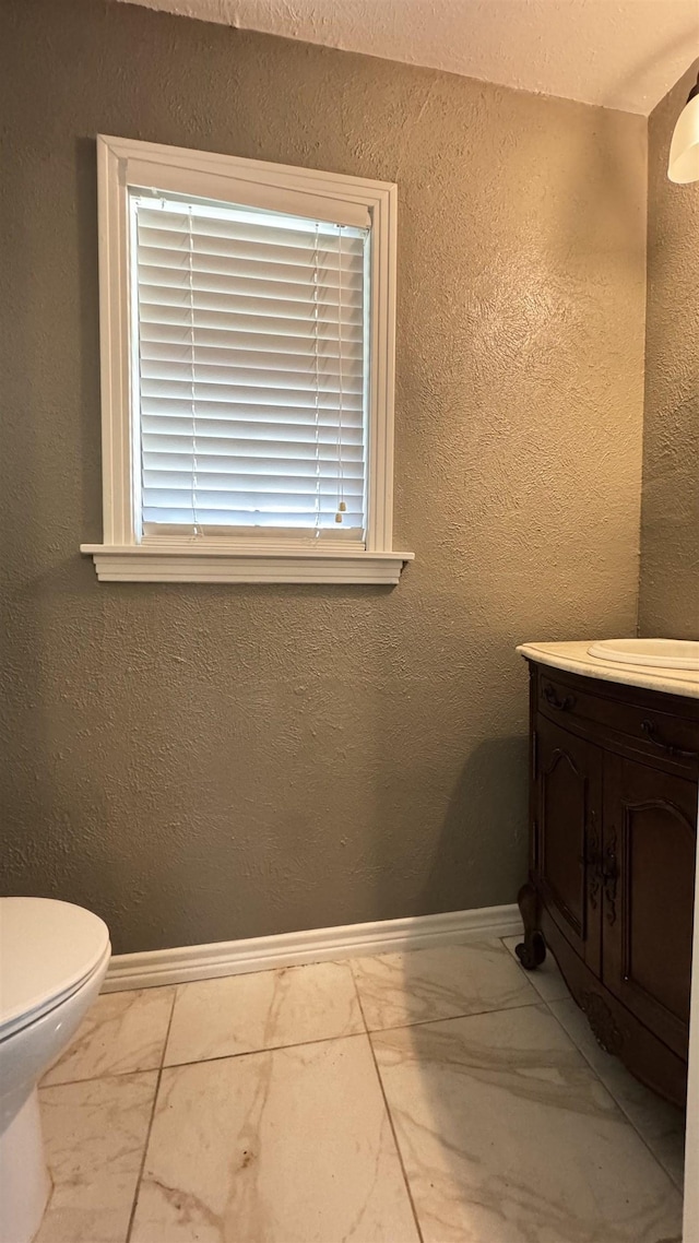4801 Kent Ave, Groves, TX 77619 - bathroom with marble finish flooring, vanity, toilet, baseboards, and a textured wall