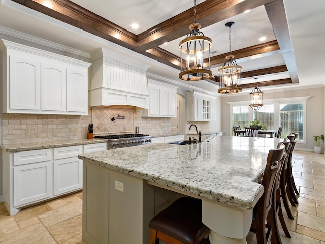 kitchen with pendant lighting, custom exhaust hood, white cabinets, a large island, and range