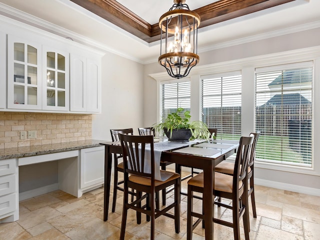 dining area featuring a raised ceiling, crown molding, and a chandelier