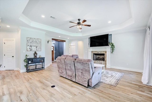 4801 Candlewick Dr, Orange, TX 77630 - living room featuring a raised ceiling, a ceiling fan, crown molding, light wood-style flooring, and a fireplace