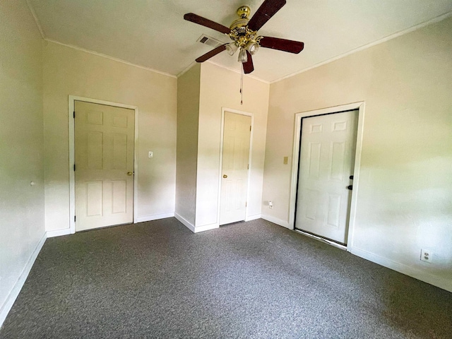 spare room with a ceiling fan, visible vents, dark colored carpet, and crown molding