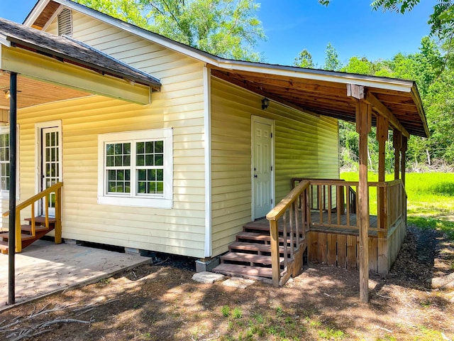view of exterior entry with roof with shingles