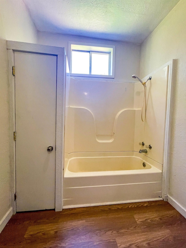 bathroom featuring baseboards, shower / bath combination, and wood finished floors