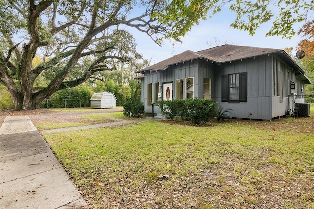 view of side of home with central AC, a storage shed, and a lawn