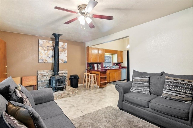 tiled living room with a wood stove, ceiling fan, and sink