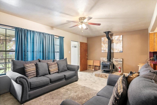 tiled living room with a textured ceiling, a wood stove, and ceiling fan