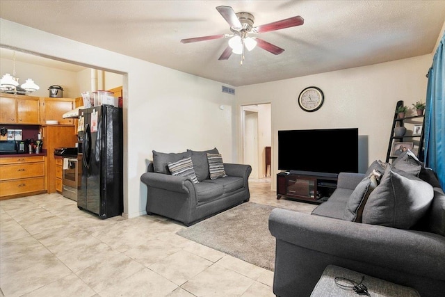 living room featuring a textured ceiling, ceiling fan with notable chandelier, and light tile patterned floors