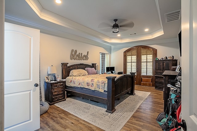 bedroom with ceiling fan, dark hardwood / wood-style floors, a raised ceiling, and french doors