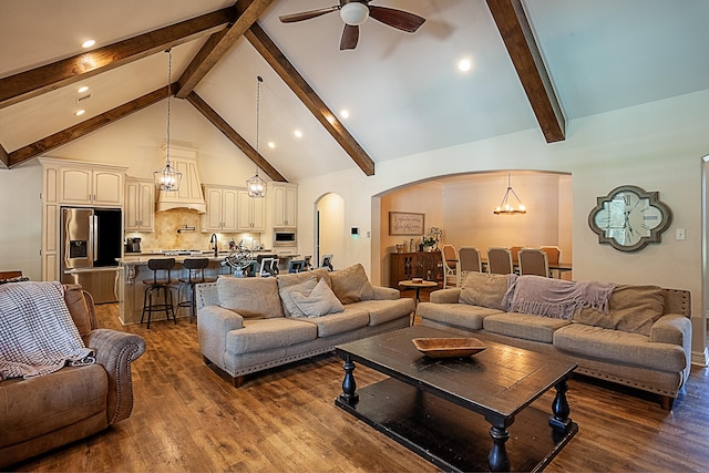 living room with sink, dark wood-type flooring, beamed ceiling, high vaulted ceiling, and ceiling fan with notable chandelier