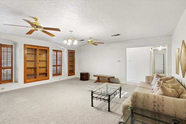 carpeted living room featuring a chandelier, built in shelves, and a textured ceiling