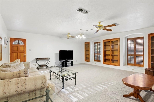 carpeted living room featuring built in shelves, ceiling fan, and a textured ceiling