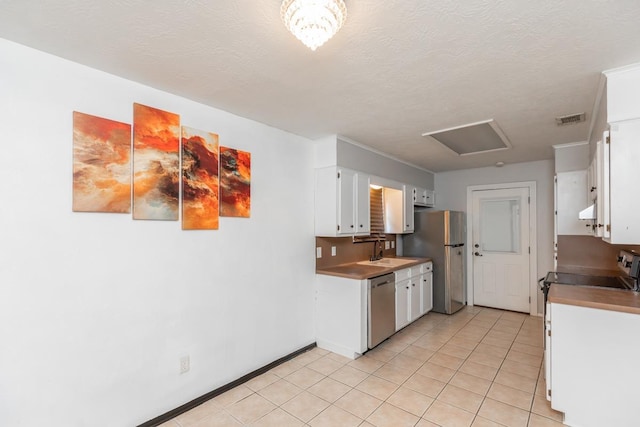 5780 Kristin Ln, Beaumont, TX 77713 - kitchen featuring appliances with stainless steel finishes, white cabinetry, ventilation hood, light tile patterned floors, and a textured ceiling
