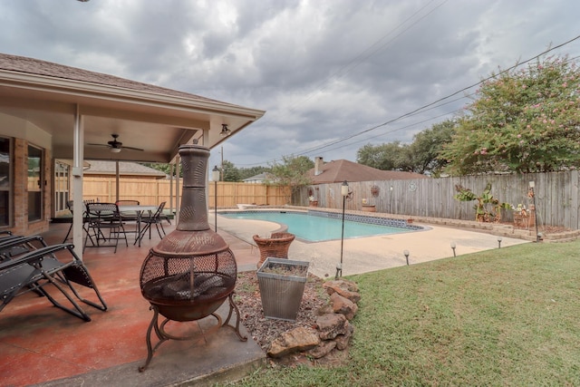 view of pool featuring a lawn, a patio area, ceiling fan, and an outdoor fire pit