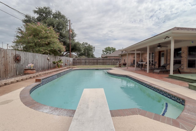 view of pool with ceiling fan, a diving board, and a patio area