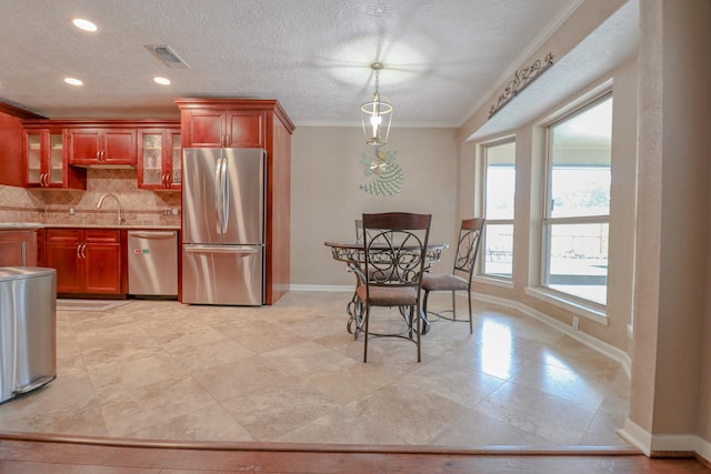 kitchen with tasteful backsplash, ornamental molding, a textured ceiling, stainless steel appliances, and sink