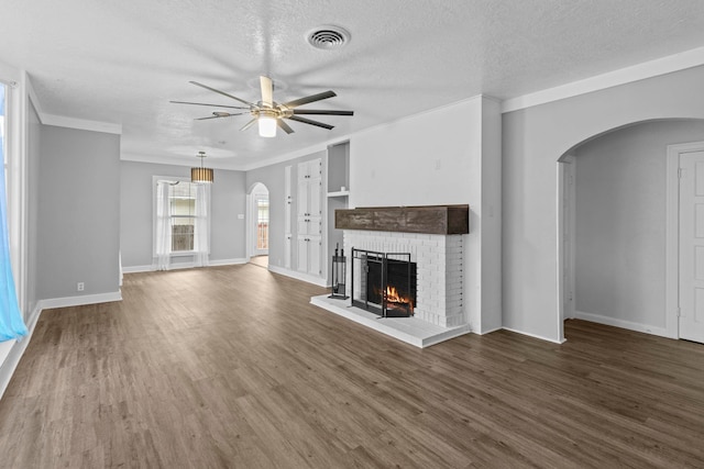 2695 Sandlin St, Beaumont, TX 77707 - unfurnished living room featuring arched walkways, a ceiling fan, a brick fireplace, wood finished floors, and crown molding