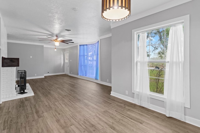 2695 Sandlin St, Beaumont, TX 77707 - unfurnished living room featuring plenty of natural light, wood finished floors, ceiling fan, a fireplace, and a textured ceiling