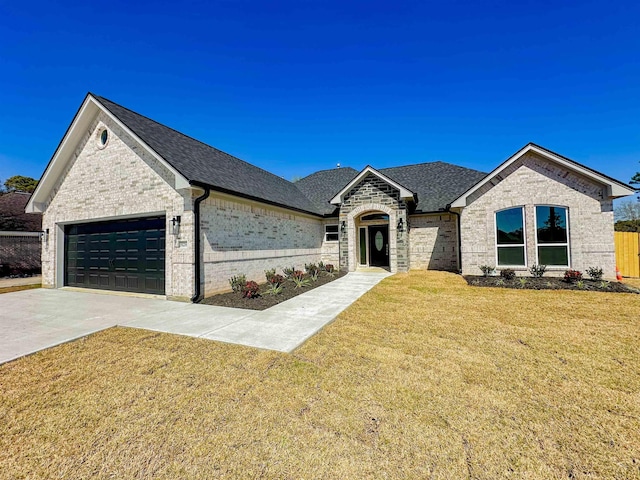 view of front of property with driveway, roof with shingles, a front lawn, a garage, and brick siding