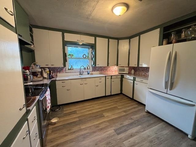 885 E Fm 1943 E, Warren, TX 77664 - kitchen featuring white appliances, wood finished floors, white cabinets, and light countertops