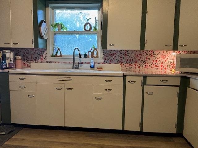 885 E Fm 1943 E, Warren, TX 77664 - kitchen with stainless steel microwave, light countertops, wood finished floors, and white cabinetry
