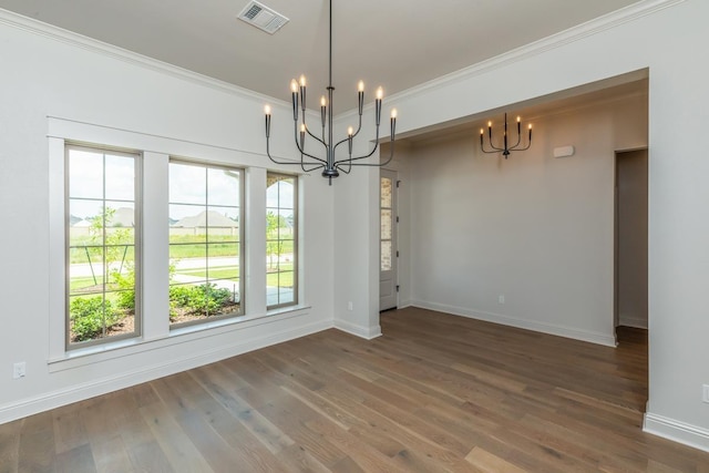 unfurnished dining area featuring wood finished floors, visible vents, crown molding, baseboards, and a chandelier